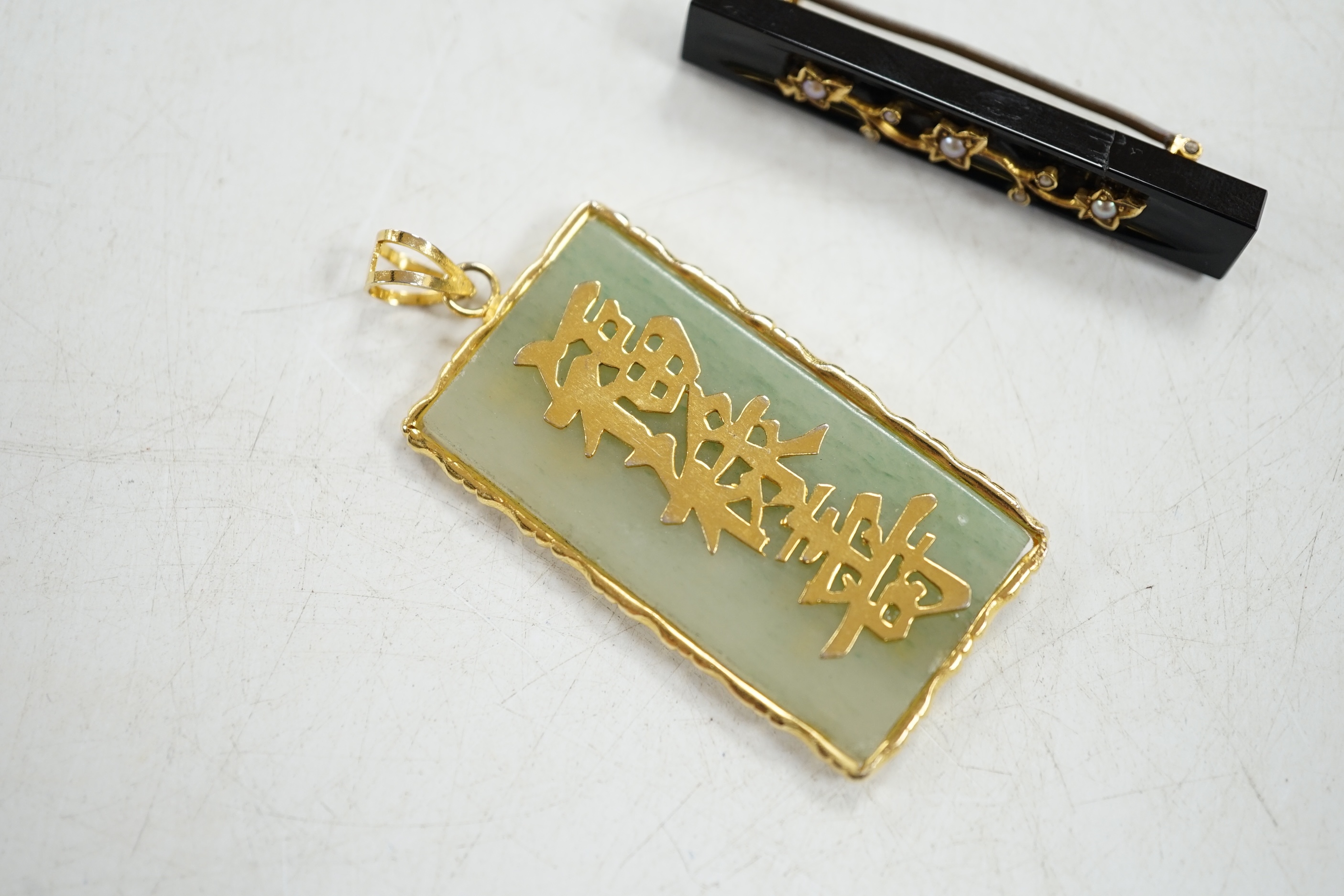 A late Victorian gold mounted black onyx and pearl bar brooch, and a Chinese yellow metal mounted jadeite pendant. Condition - fair